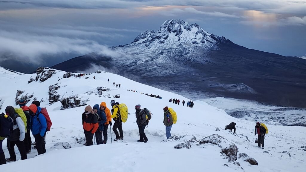Climbers trekking to the summit of Mount Kilimanjaro with snow-covered peak in Tanzania
