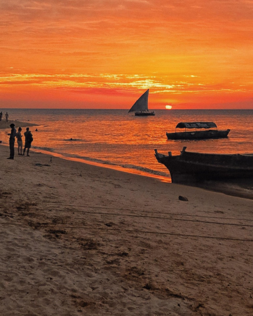 Zanzibar sunset with traditional dhow boat on the beach Tanzania