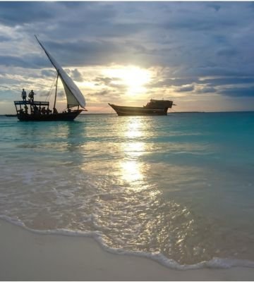 Traditional dhow boat at sunset on Zanzibar beach Tanzania